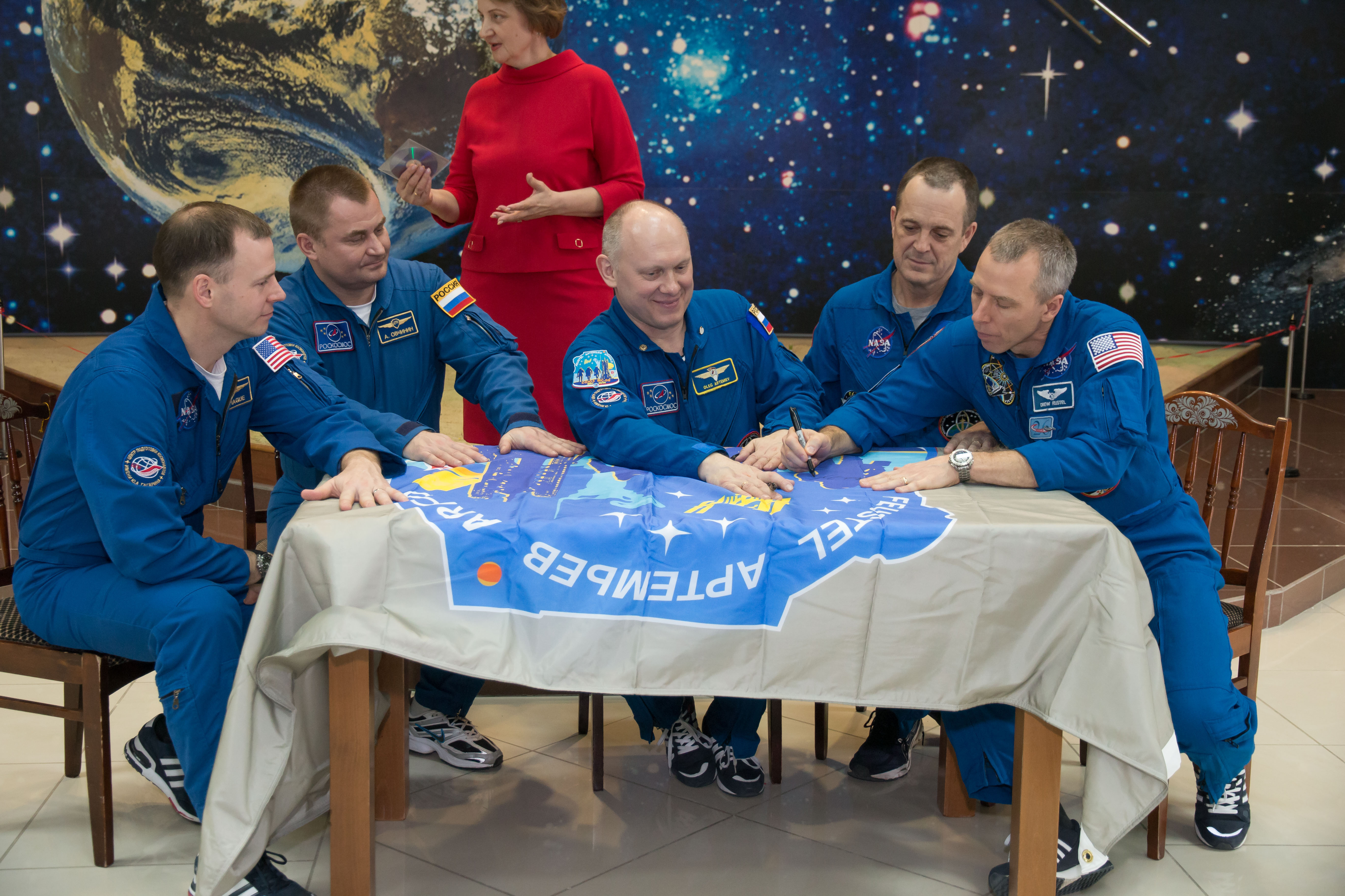 In the Korolev Museum at the Baikonur Cosmodrome in Kazakhstan, the Expedition 55 prime and backup crew members sign a flag bearing their Soyuz MS-08 crew patch insignia March 16 during a traditional preflight tour of the museum. From left to right are backup crewmembers Nick Hague of NASA and Alexey Ovchinin of Roscosmos and prime crewmembers Oleg Artemyev of Roscosmos, Ricky Arnold of NASA and Drew Feustel of NASA, who will launch March 21 on the Soyuz MS-08 spacecraft for a five-month mission on the International Space Station.
