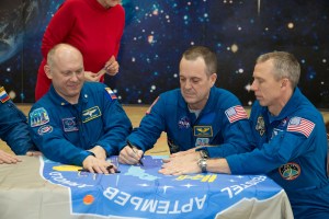 In the Korolev Museum at the Baikonur Cosmodrome in Kazakhstan, the Expedition 55 prime and backup crew members sign a flag bearing their Soyuz MS-08 crew patch insignia March 16 during a traditional preflight tour of the museum. From left to right are backup crewmembers Nick Hague of NASA and Alexey Ovchinin of Roscosmos and prime crewmembers Oleg Artemyev of Roscosmos, Ricky Arnold of NASA and Drew Feustel of NASA, who will launch March 21 on the Soyuz MS-08 spacecraft for a five-month mission on the International Space Station.