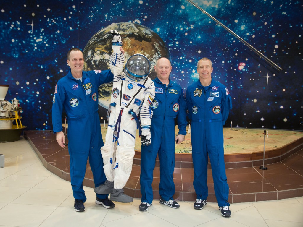In the Korolev Museum at the Baikonur Cosmodrome in Kazakhstan, Expedition 55 crew members Ricky Arnold of NASA (left), Oleg Artemyev of Roscosmos (center) and Drew Feustel of NASA (right) display the Russian Sokol launch and entry suit worn by Artemyev during his first flight into space in 2014 as part of the Expedition 39-40 crew. Artemyev is donating the suit to the museum as an historical artifact. The crewmembers will launch March 21 on the Soyuz MS-08 spacecraft for a five-month mission on the International Space Station.