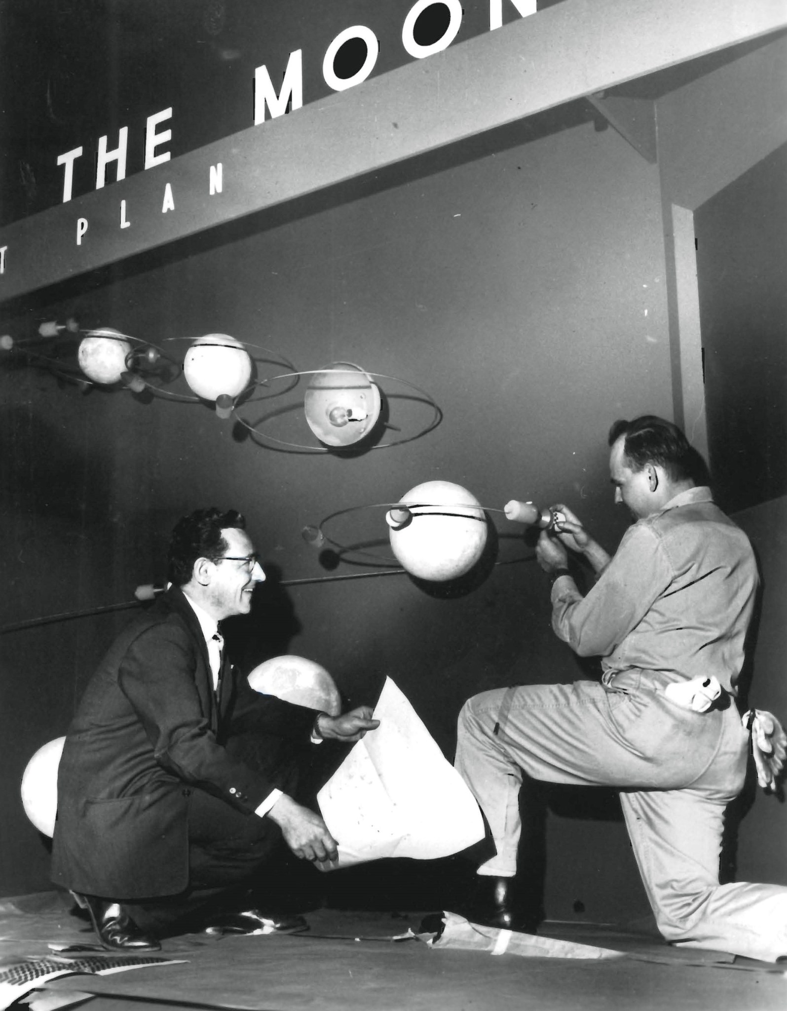 Two men kneeling to work on exhibit.