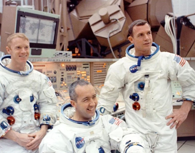 Apollo 9 astronauts Russell L. Schweickart, left, James A. McDivitt, and David R. Scott pose in front of the control panel for the spacecraft simulators