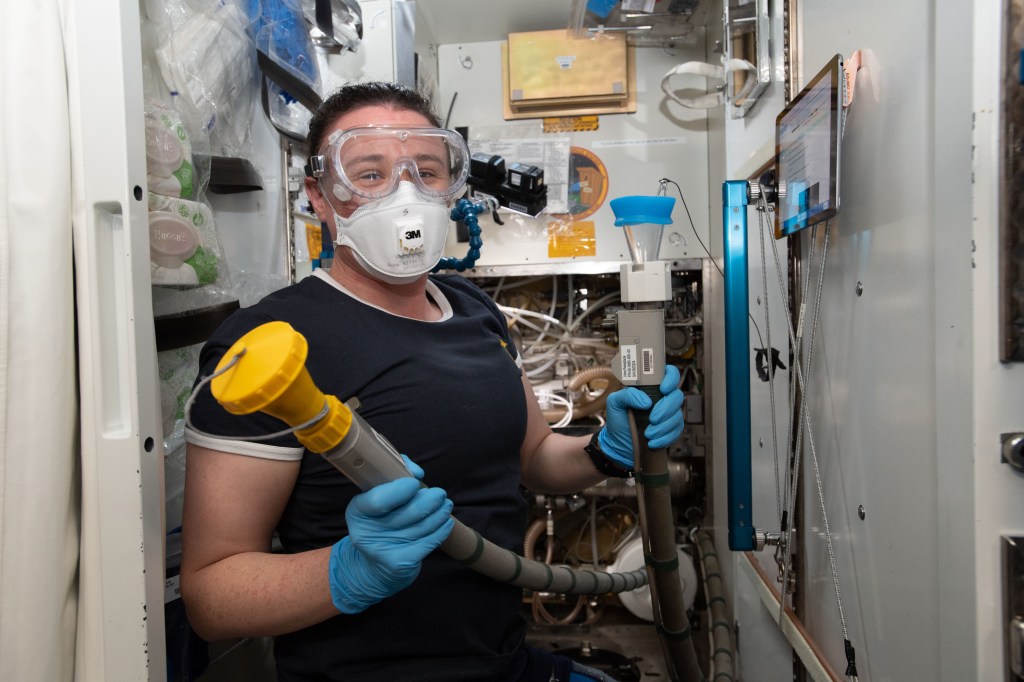 NASA astronaut Serena Auñón-Chancellor performs plumbing duties inside the International Space Station's toilet, also known as the Waste and Hygiene Compartment, located in the U.S. Tranquility module.