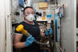 NASA astronaut Serena Auñón-Chancellor performs plumbing duties inside the International Space Station's toilet, also known as the Waste and Hygiene Compartment, located in the U.S. Tranquility module.