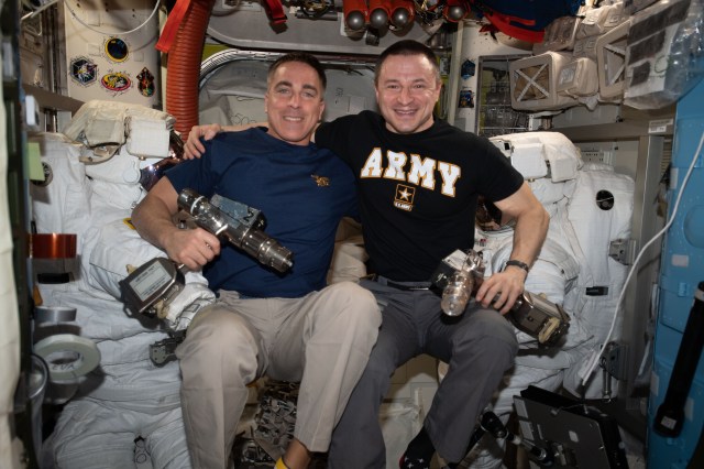 iss062e147776 (April 12, 2020) --- NASA astronauts (from left) Chris Cassidy and Andrew Morgan take a break and pose for a portrait inside the Quest airlock during maintenance on U.S. spacesuits. Cassidy is a U.S. Navy SEAL and Captain. Morgan is an emergency physician and Colonel in the U.S. Army.