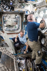 NASA astronauts Drew Feustel and Scott Tingle are at work inside the U.S. Destiny laboratory module. Feustel works on routing and installing ethernet cables throughout the International Space Station. Tingle conducts research for the Metabolic Tracking experiment inside the lab module's Microgravity Science Glovebox.