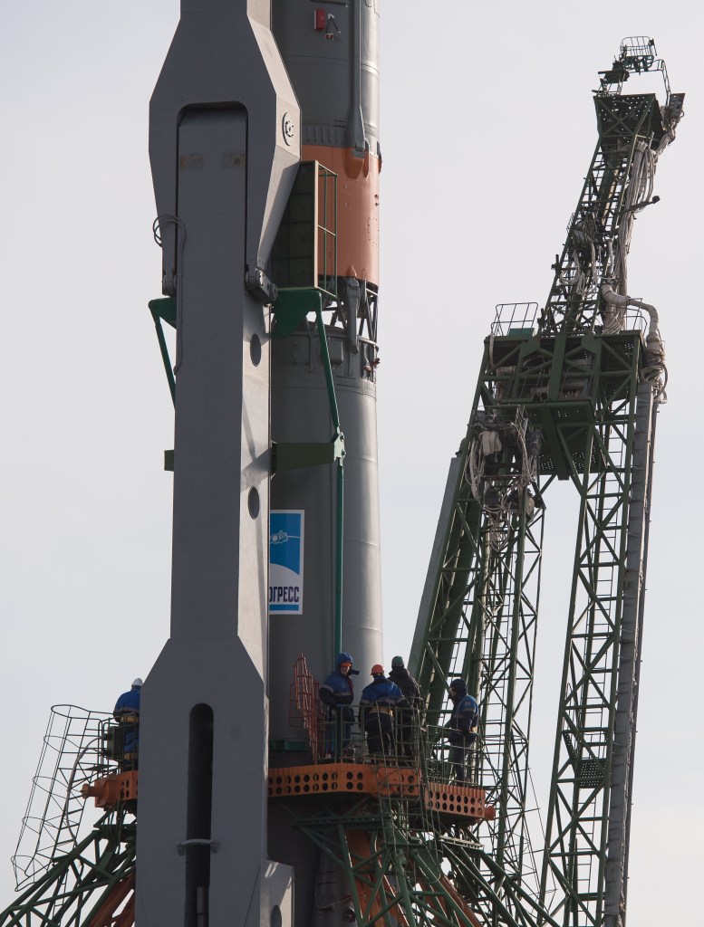 Workers are seen on a gantry after the Soyuz rocket was raised into a vertical position on the launch pad, Monday, March 19, 2018 at the Baikonur Cosmodrome in Kazakhstan. Expedition 55 crewmembers Ricky Arnold and Drew Feustel of NASA and Oleg Artemyev of Roscosmos are scheduled to launch at 1:44 p.m. Eastern time (11:44 p.m. Baikonur time) on March 21 and will spend the next five months living and working aboard the International Space Station.