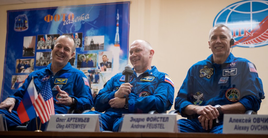 Expedition 55 prime crew members Ricky Arnold of NASA, left, Oleg Artemyev of Roscosmos, center, and Drew Feustel of NASA, right, are seen in quarantine, behind glass, during a press conference, Tuesday, March 20, 2018 a the Cosmonaut Hotel in Baikonur, Kazakhstan. Expedition 55 Soyuz Commander Oleg Artemyev of Roscosmos, Ricky Arnold and Drew Feustel of NASA are scheduled to launch to the International Space Station aboard the Soyuz MS-08 spacecraft on Wednesday, March 21.