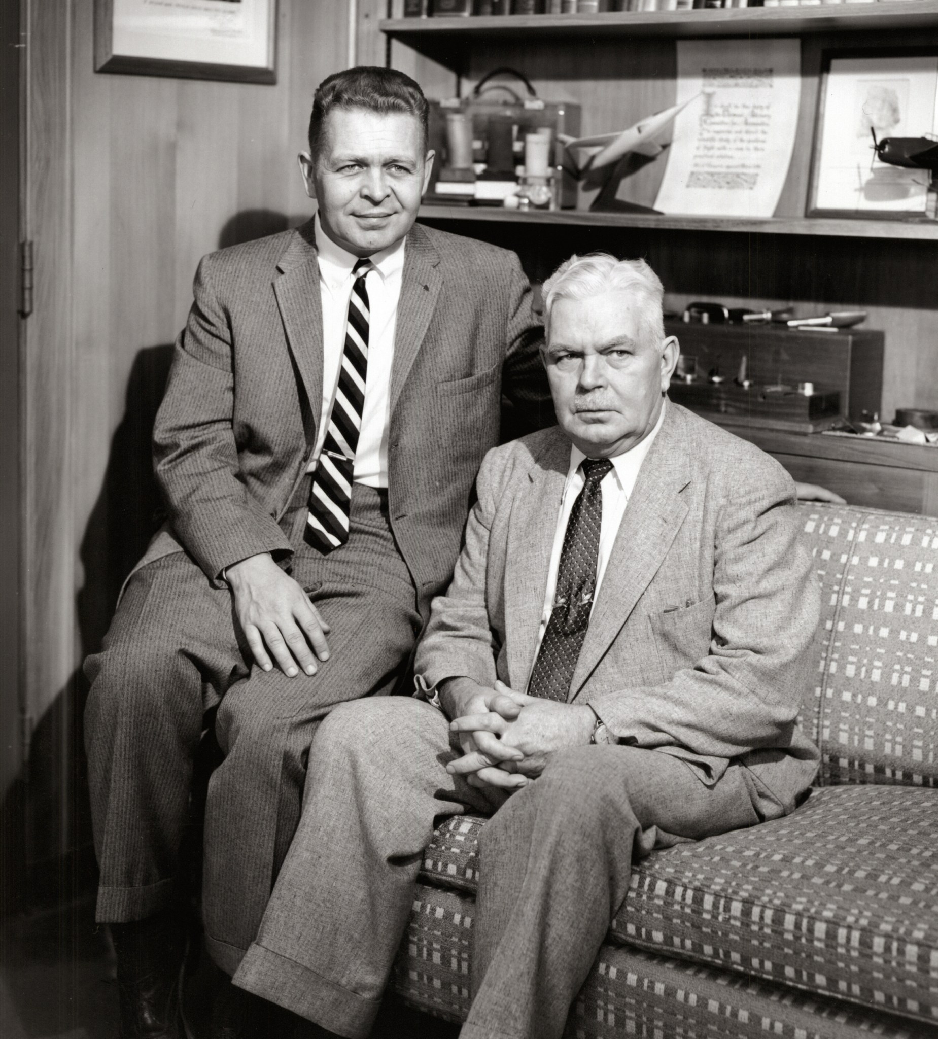 Two men seated on couch.
