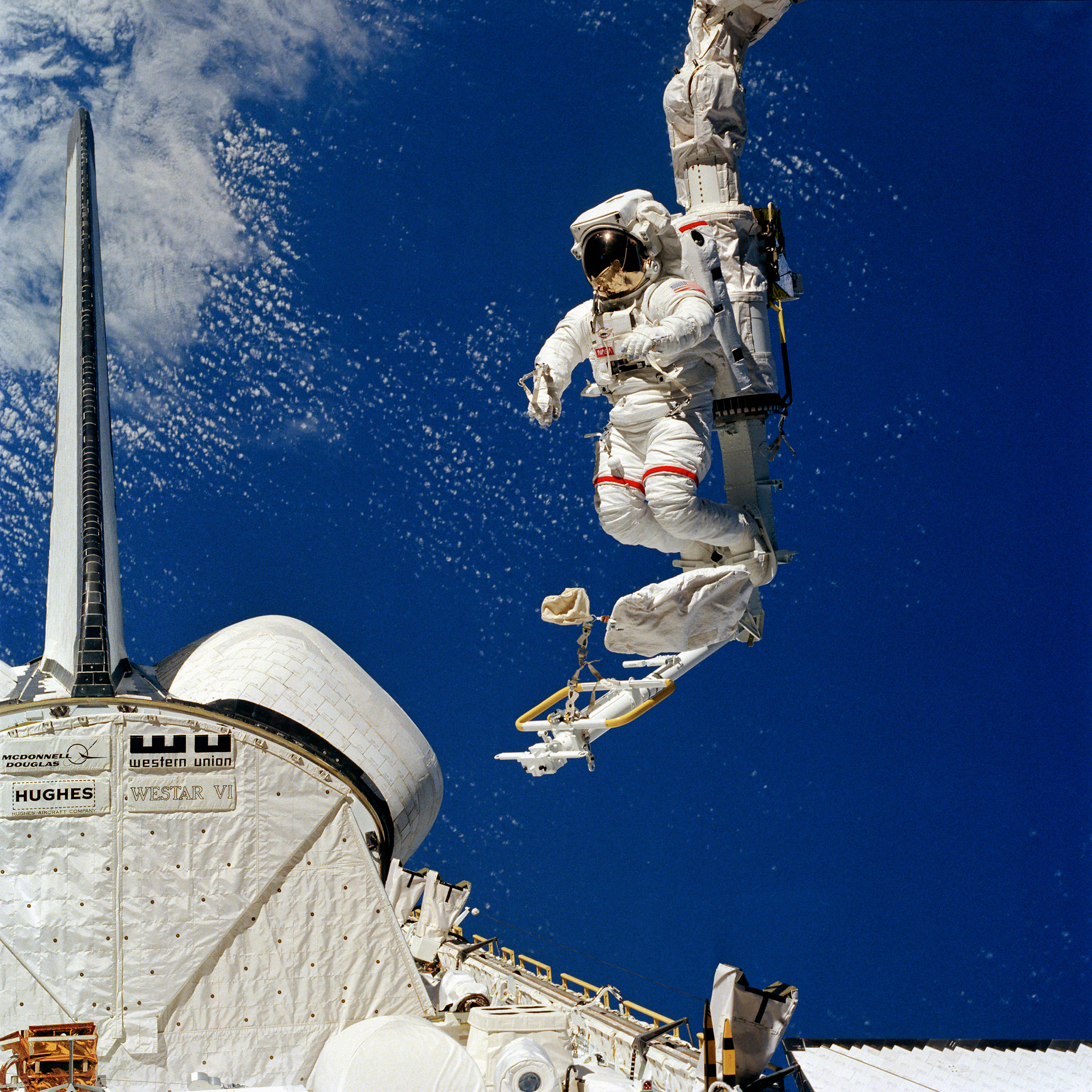 View of Bruce McCandless testing the Manipulator Foot Restraint at the end of the Remote Manipulator System, operated by Ronald E. McNair