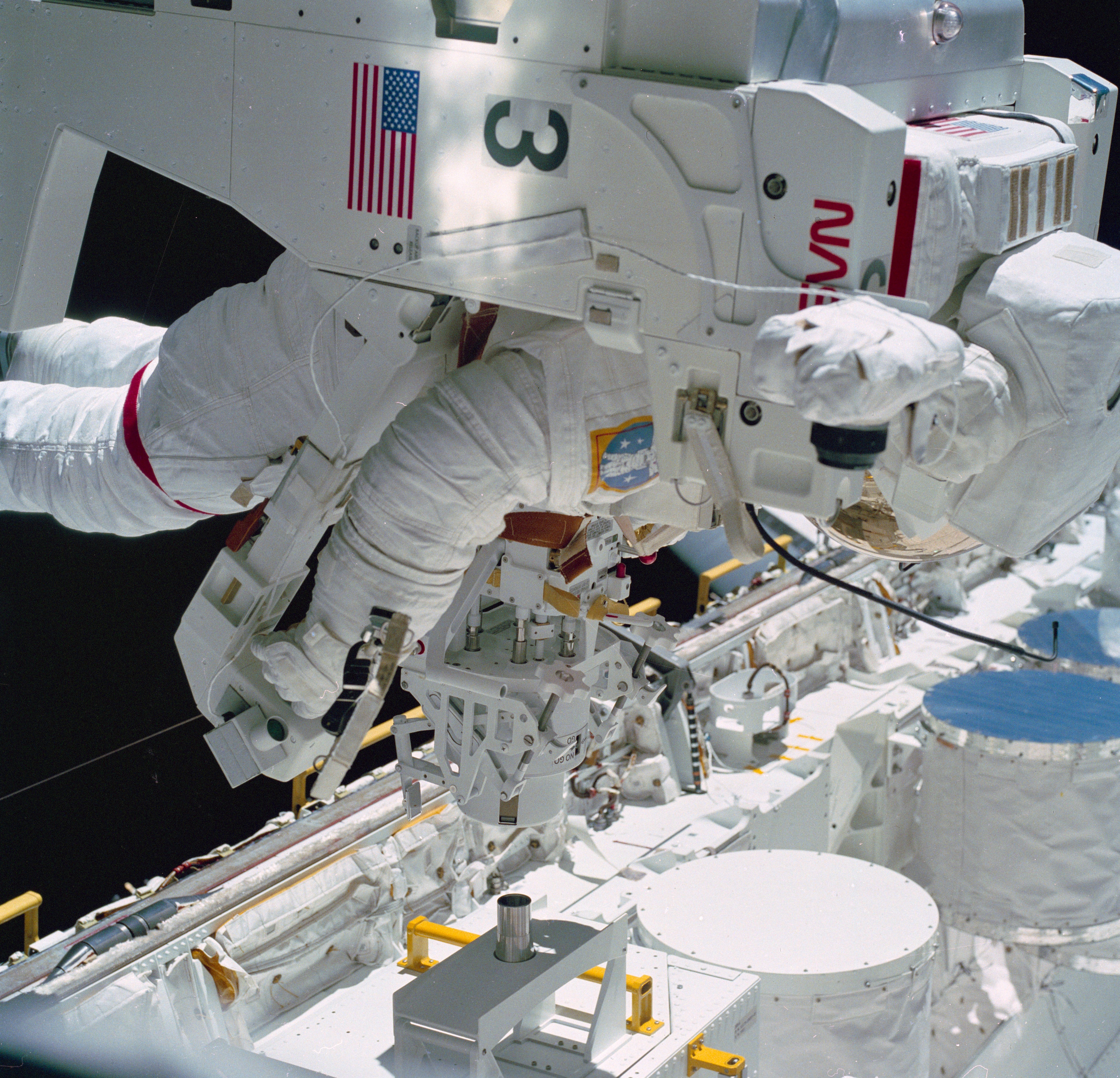 Bruce McCandless prepares to dock his MMU with the attached Trunnion Pin Attachment Device to the SPAS-01A in Challenger’s payload bay