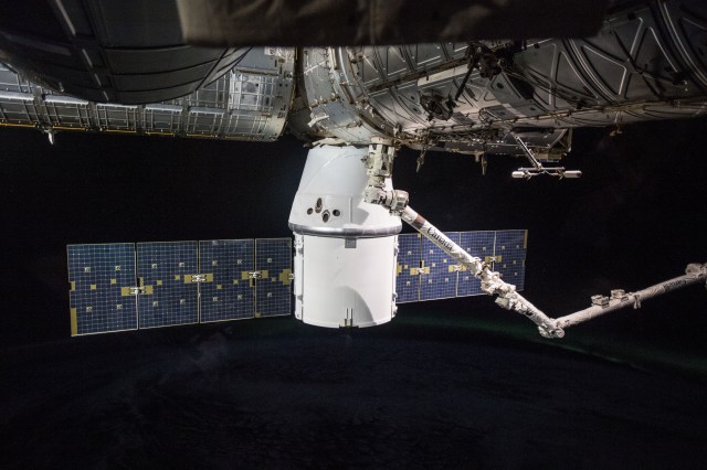 The SpaceX Dragon resupply ship, with the 57.7-foot-long Canadarm2 robotic arm in the foreground, is pictured installed to the Harmony module's Earth-facing port.