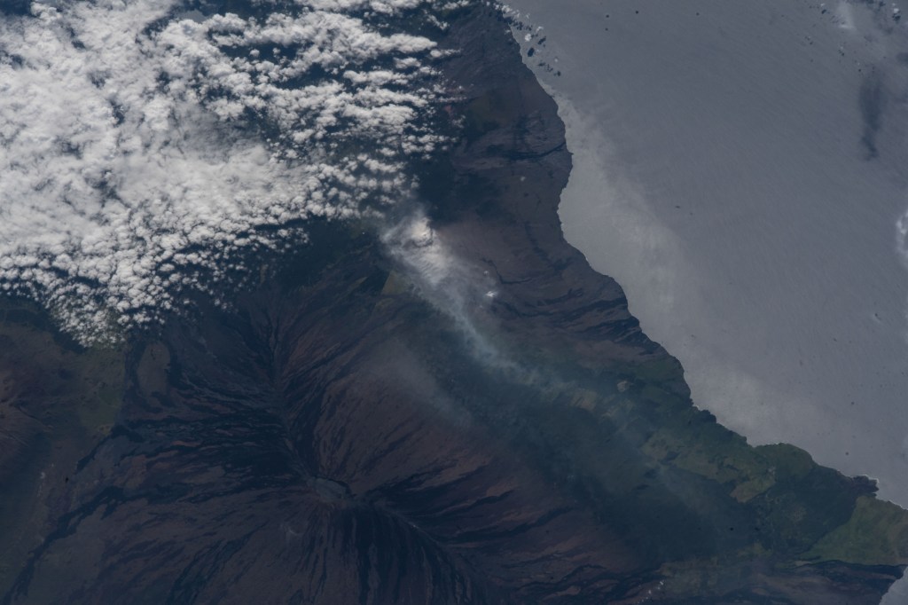 The volcanic ash plume from Mount Kilauea is seen just inland off the eastern coast of Hawaii's Big Island.