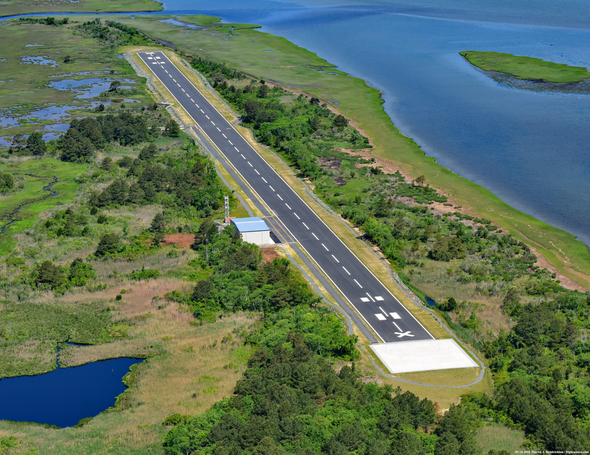 An east to west aerial photograph of the Unmanned Aerial System (UAS) Airstrip surrounded by vegetation and water, on the northern end of NASA Wallops Flight Facility's Wallops Island in Accomack County, Virginia.