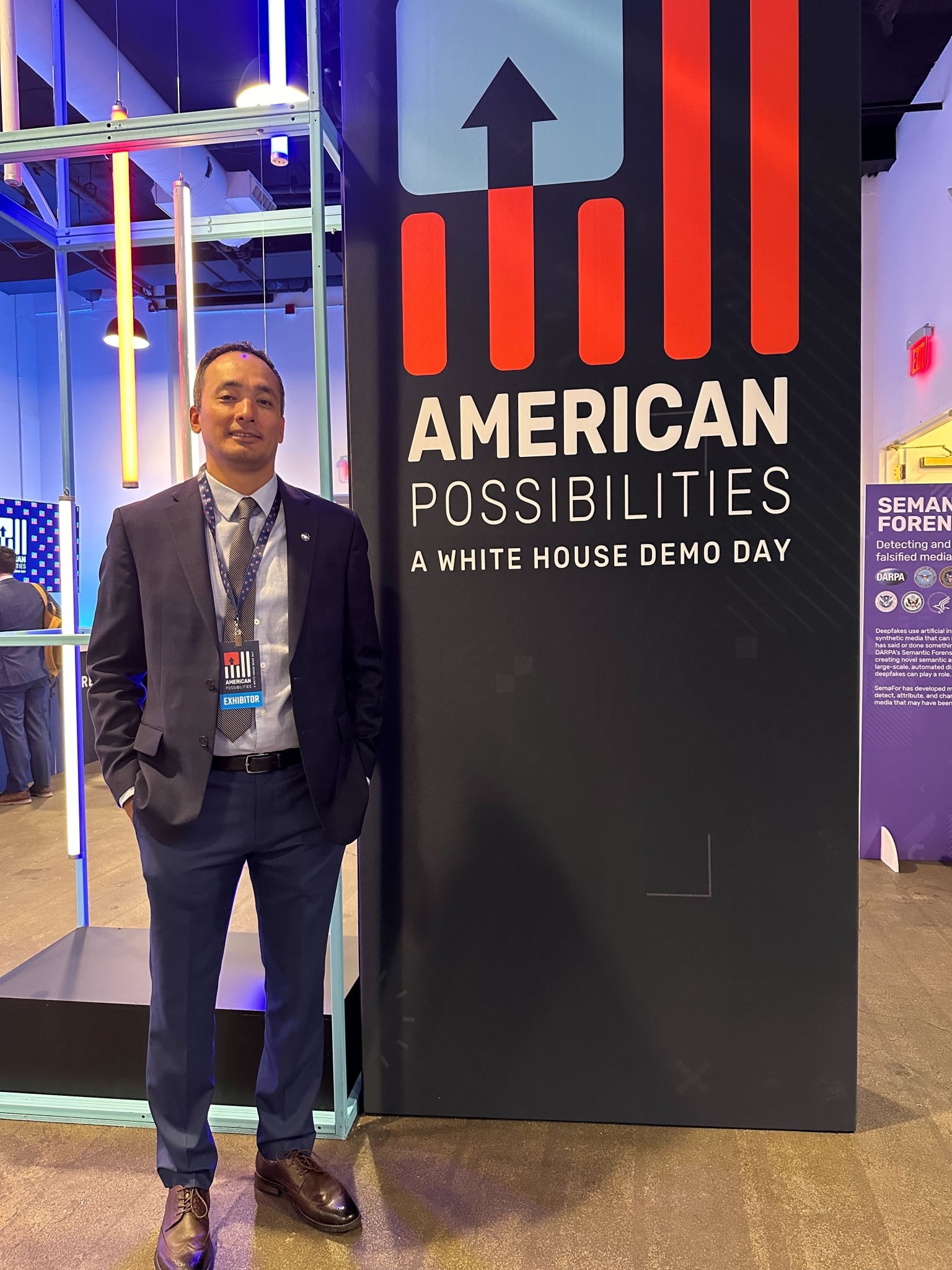 Manil Maskey stands next to a banner during White House Demo Day last November.