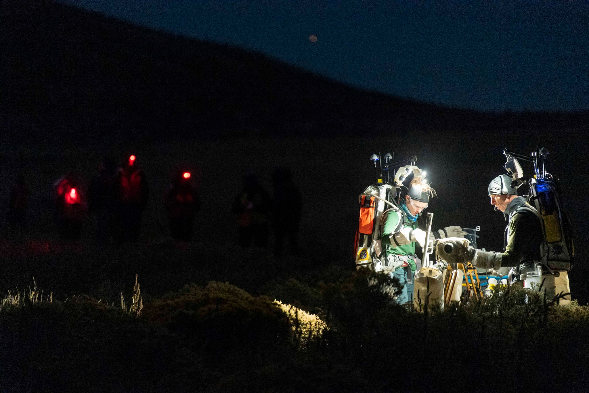 NASA astronauts Zena Cardman and Drew Feustel practice using an early design of the Handheld Universal Lunar Camera during the Joint Extravehicular Activity and Human Surface Mobility Test Team (JETT) Field Test 3 in Arizona.