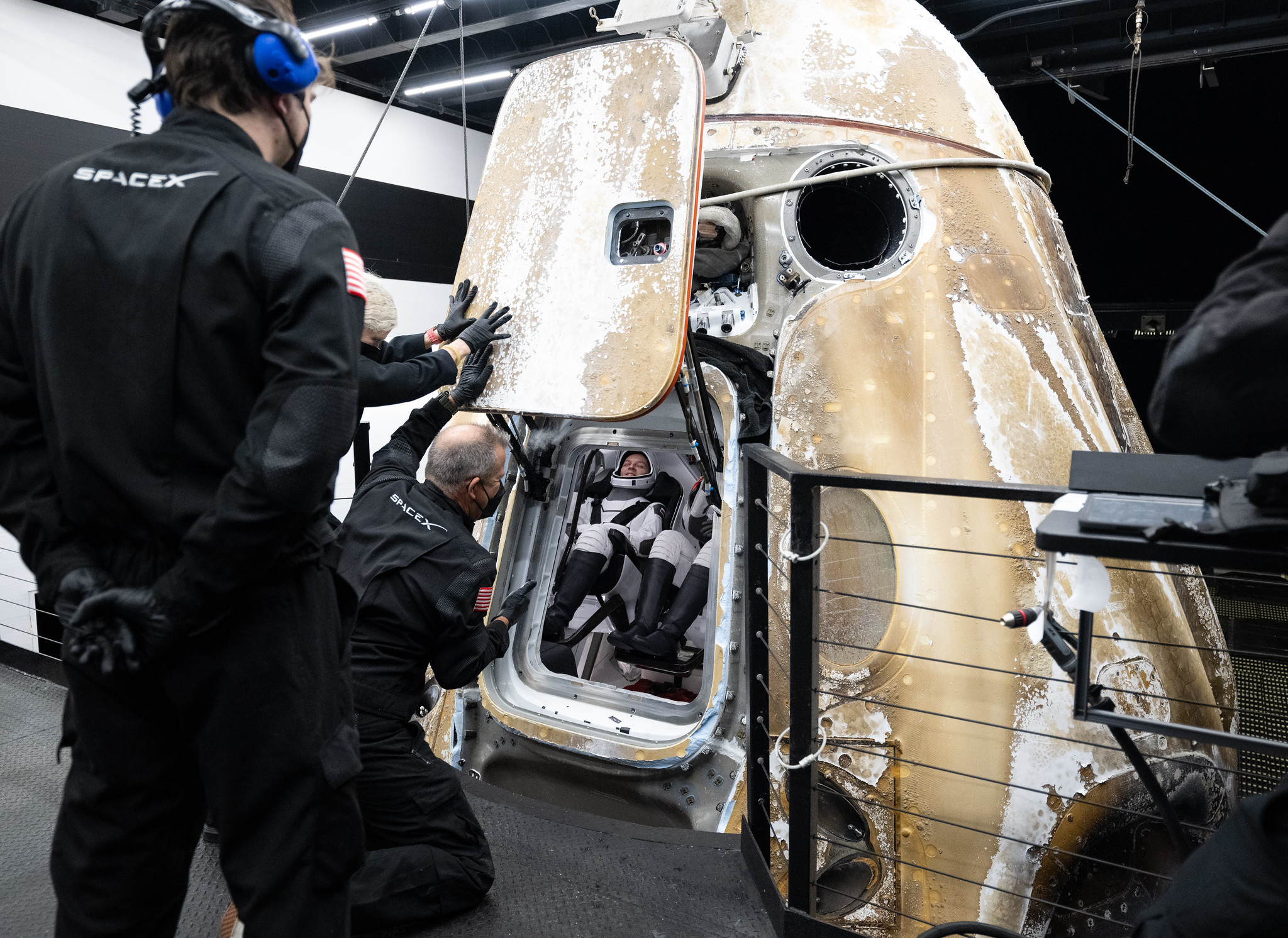 Support teams onboard the SpaceX recovery ship MEGAN work around the SpaceX Dragon Endurance spacecraft after the hatch was opened shortly after it landed.