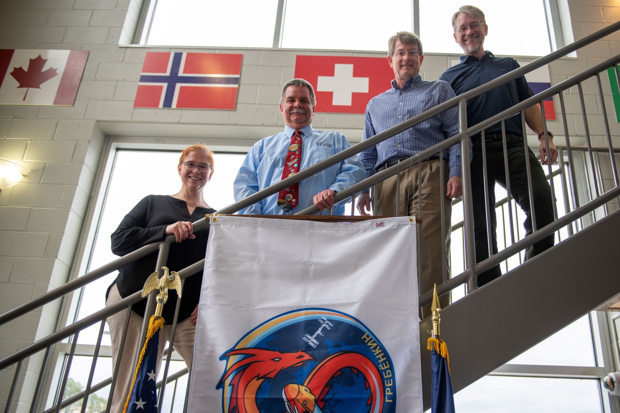 From left, Pelfrey, Oelkers, Earhart, and Gwaltney smile together after hanging the Crew-8 mission flag.