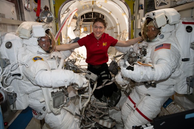 iss060e038215 (Aug. 21, 2019) --- NASA astronaut Christina Koch poses for a portrait with Andrew Morgan and Nick Hague in their U.S. spacesuits before beginning a six-hour and 32-minute spacewalk to install the orbiting lab’s second commercial crew vehicle docking port, the International Docking Adapter-3 (IDA-3). The IDA-3 will accommodate the future arrivals of Boeing CST-100 Starliner and SpaceX Crew Dragon commercial crew spacecraft.