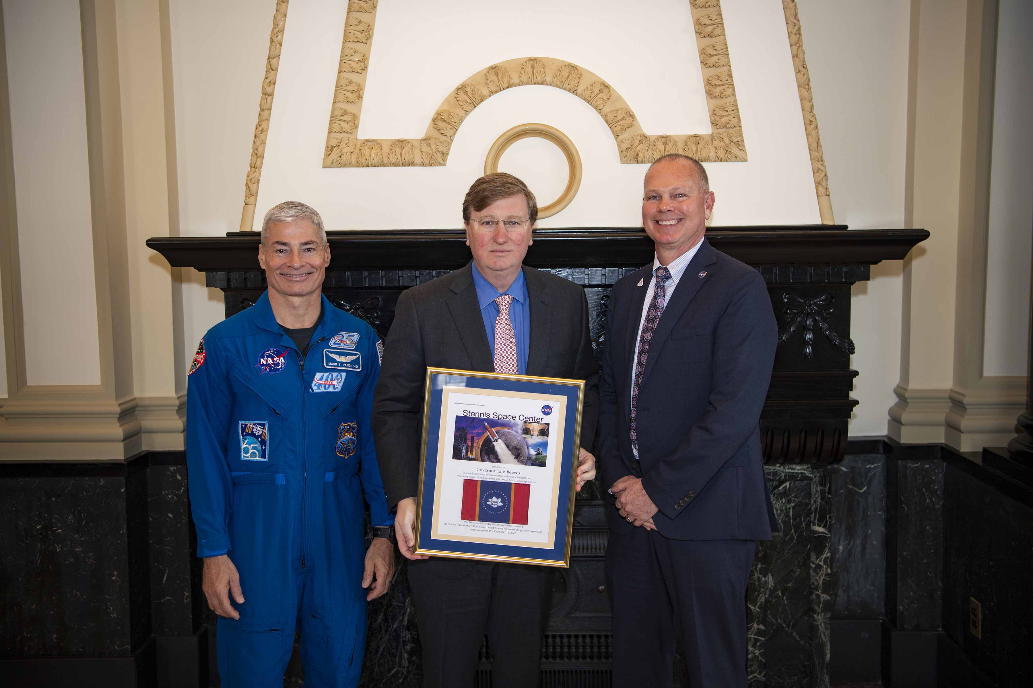 NASA astronaut Mark Vande Hei, Mississippi Gov. Tate Reeves, and NASA Stennis Acting Center Director John Bailey with a plaque presented to the governor for Mississippi’s support of NASA Stennis