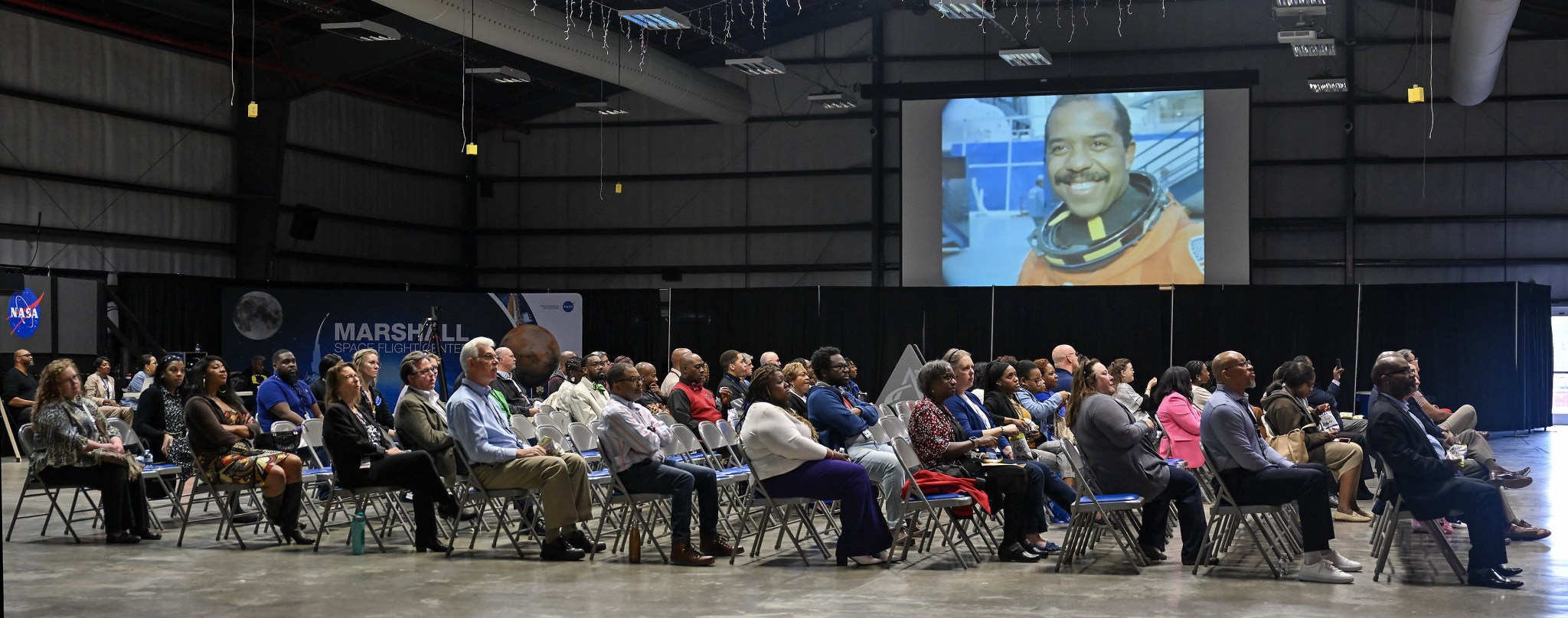 Attendees at BEAM’s Black History Month observance event Feb. 27 watch the NASA documentary “The Color of Space.” On screen is former NASA astronaut Bernard A. Harris Jr., who flew during the Space Shuttle Program. He has logged 438 hours in space.