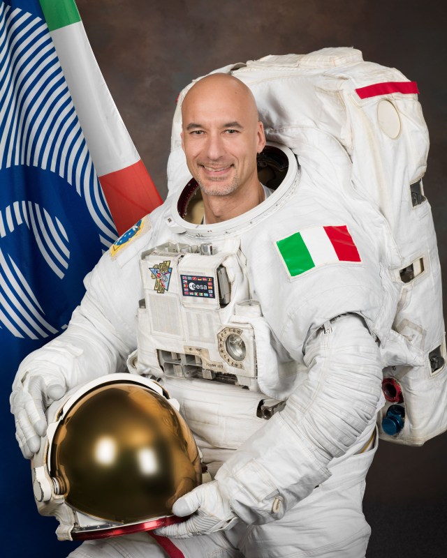 jsc2013e007948 (Jan. 25, 2013) --- ESA (European Space Agency) astronaut Luca Parmitano poses for his official portrait in a U.S. spacesuit at NASA's Johnson Space Center. A patch bearing the flag of his home country of Italy is attached to the spacesuit. The ESA and Italian flags are also in the left background.