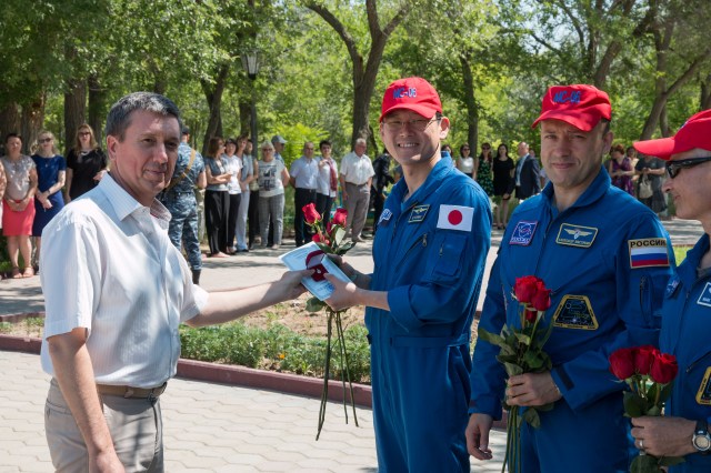 At their Cosmonaut Hotel crew quarters in Baikonur, Kazakhstan, Expedition 52-53 backup crewmembers Norishige Kanai of the Japan Aerospace Exploration Agency (JAXA, left), Alexander Misurkin of the Russian Federal Space Agency (Roscosmos, center) and Mark Vande Hei of NASA (right) accept flowers during a traditional flag-raising ceremony July 18. They are serving as backups to Randy Bresnik of NASA, Sergey Ryazanskiy of Roscosmos and Paolo Nespoli of the European Space Agency, who will launch July 28 on the Soyuz MS-05 spacecraft from the Baikonur Cosmodrome for a five-month mission on the International Space Station.