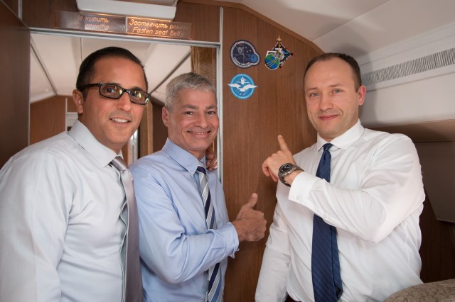 Aboard the Gagarin Cosmonaut Training Center Aircraft en route from their training base to their launch site at the Baikonur Cosmodrome in Kazakhstan for final pre-launch training, Expedition 53-54 crewmembers Joe Acaba (left) and Mark Vande Hei (center) of NASA and Alexander Misurkin of Roscosmos (right) point to the stickers bearing their mission insignias Sept. 6. They will launch Sept. 13 on the Soyuz MS-06 spacecraft from the Baikonur Cosmodrome for a five and a half month mission on the International Space Station.