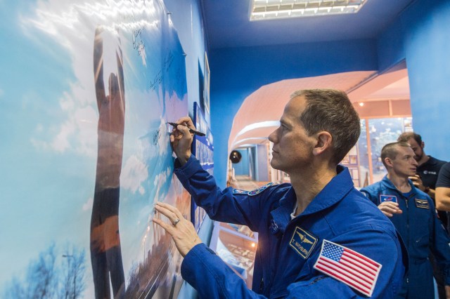 jsc2019e038394 (July 6, 2019) --- At the Baikonur Museum in the town of Baikonur, Kazakhstan, Expedition 60 backup crewmember Tom Marshburn of NASA signs a wall mural July 6 during traditional pre-launch activities. In the background is crewmate Sergey Ryzhikov of Roscosmos. Marshburn, Ryzhikov and Soichi Noguchi of the Japan Aerospace Exploration Agency are the backups to the prime crew, Drew Morgan of NASA, Luca Parmitano of the European Space Agency and Alexander Skvortsov of Roscosmos, who will launch July 20 on the Soyuz MS-13 spacecraft from the Baikonur Cosmodrome in Kazakhstan for a mission on the International Space Station. Credit: Andrey Shelepin/GCTC