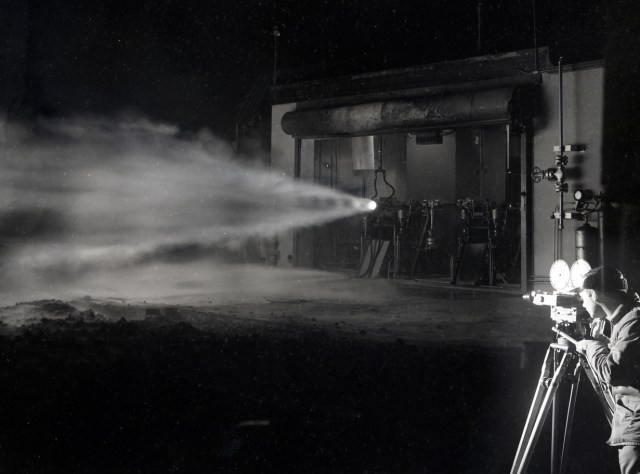 Photographer filming rocket test at night.