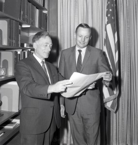 Two men examining document.