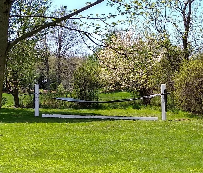 A solar panel suspended between two poles in a yard.