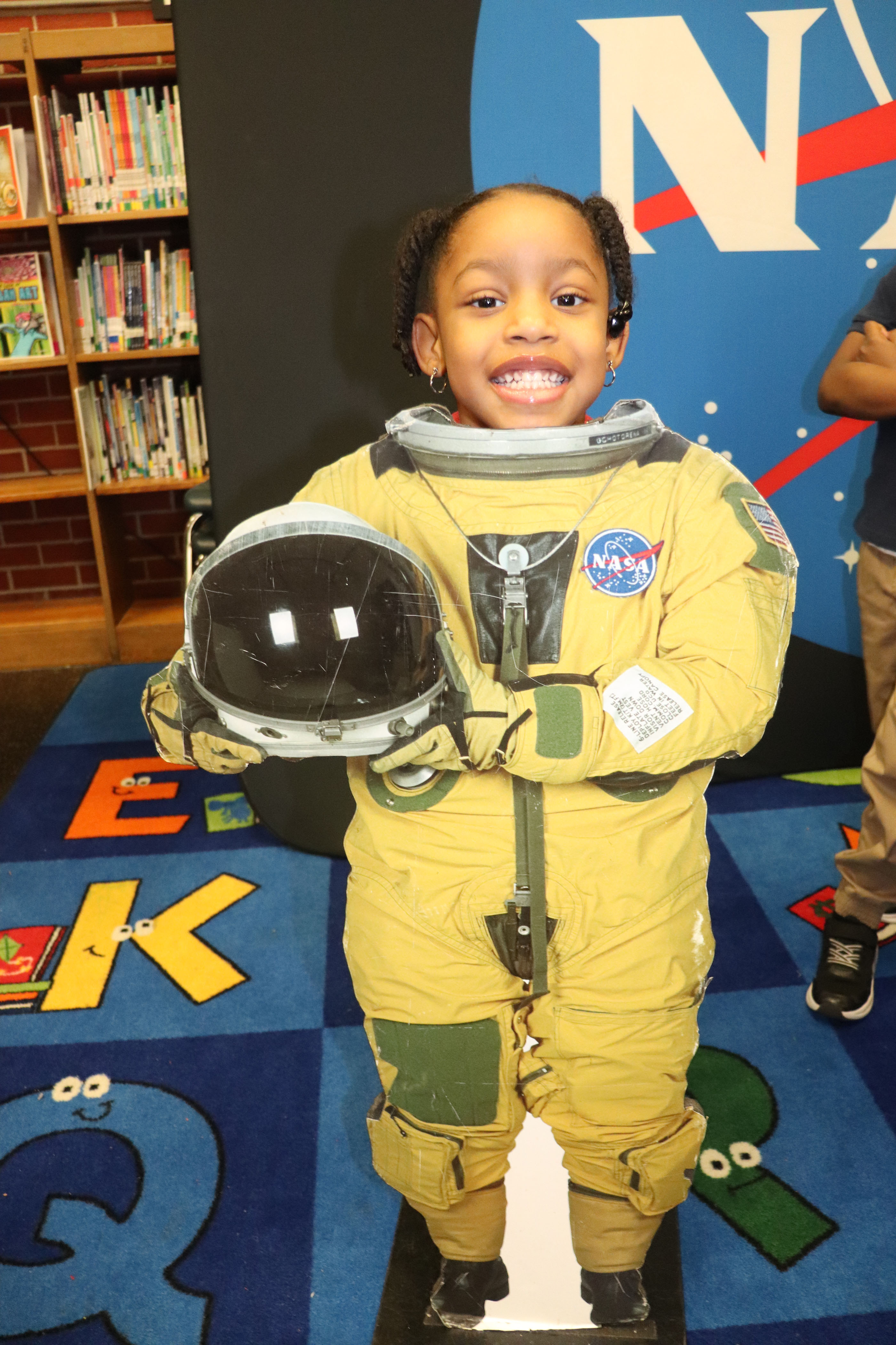 young student poses behind astronaut cutout
