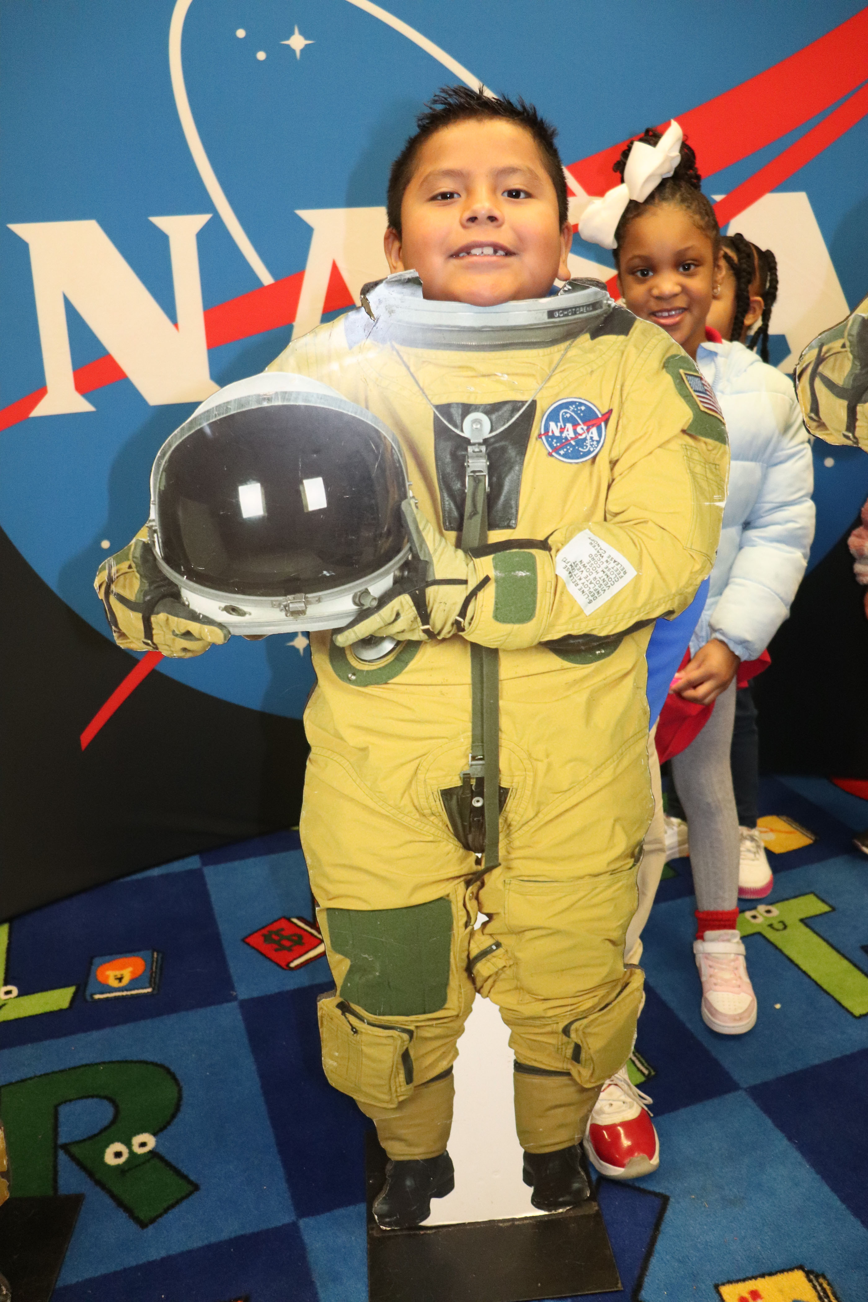 young student poses behind astronaut cutout