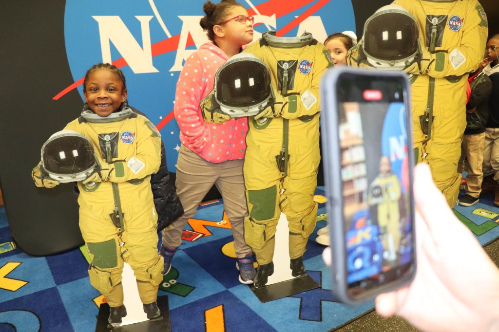 young students pose behind a trio of astronaut cutouts