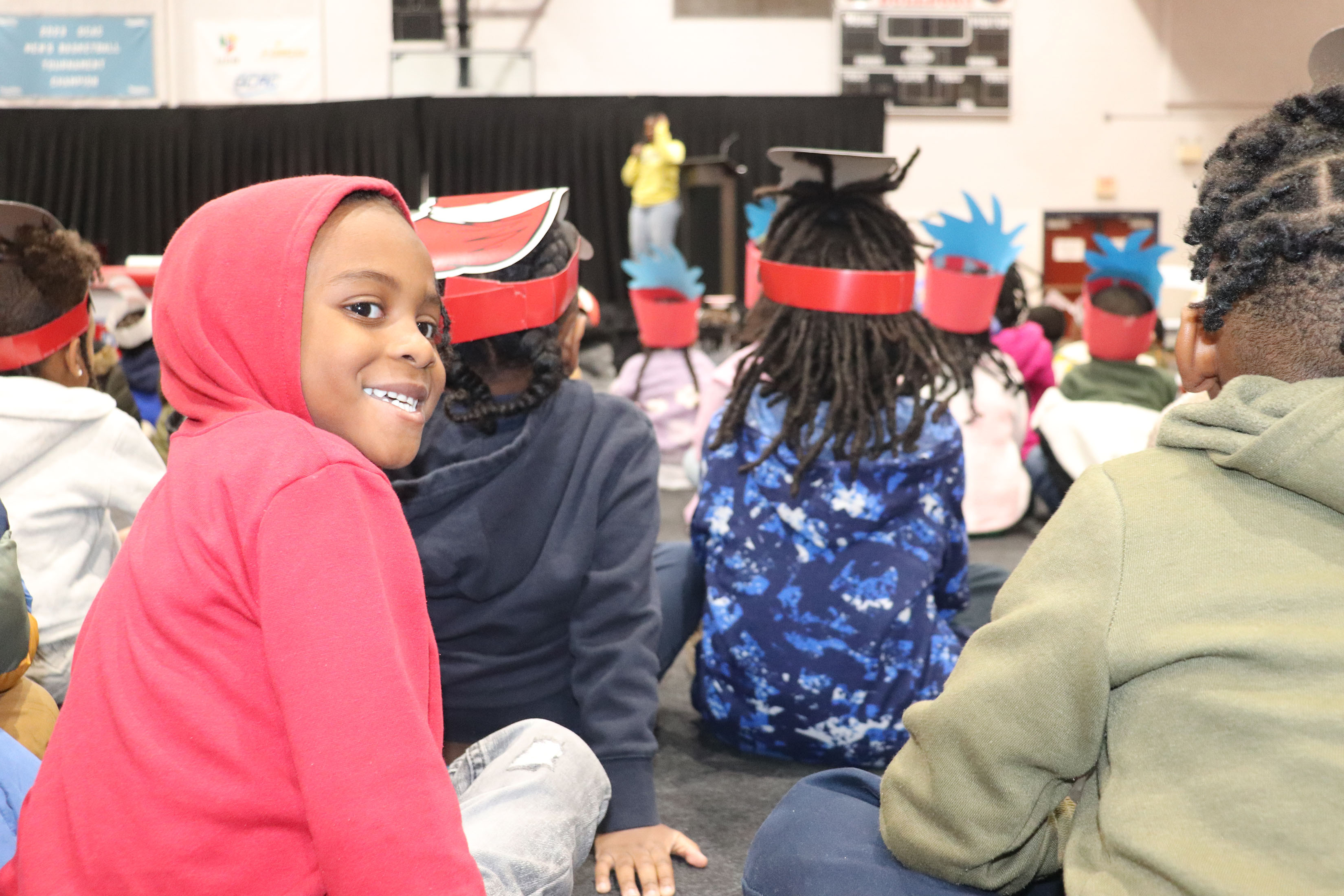 young student wearing a red hooded shirt looks back and smiles at camera