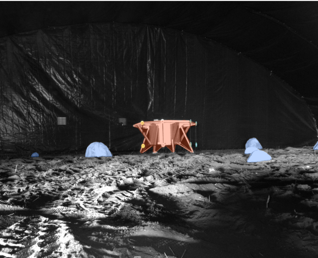 A photo taken from the ISRU Pilot Excavator as it is tested in a blacked out facility with minimal lighting that mimics the harsh, feature-less terrain of the Moon.