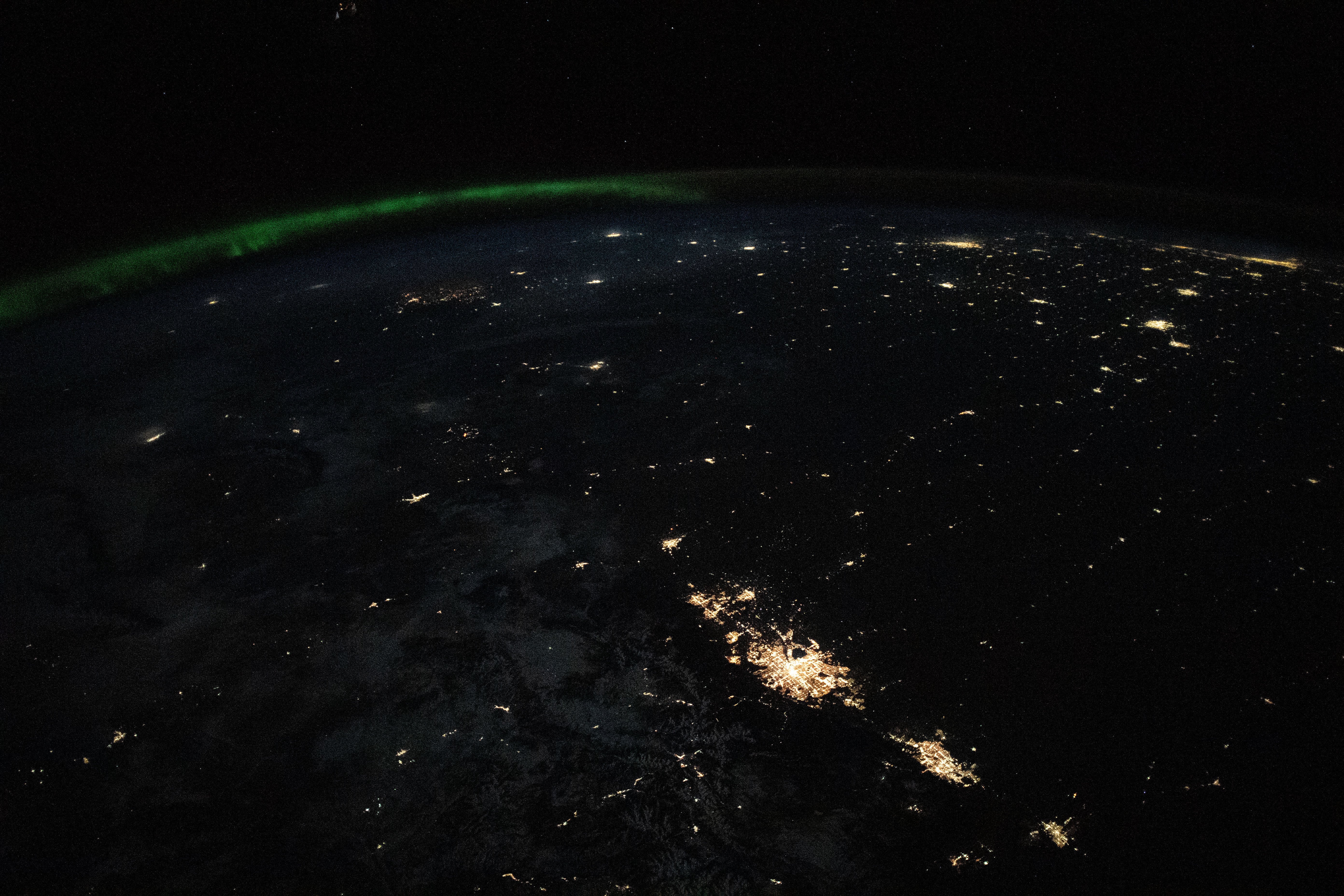 The city lights of the Denver, Colorado, area (lower right) are pictured from the International Space Station as it orbited 262 miles above the southwestern United States. At top left, an aurora crowns a portion of Canada.