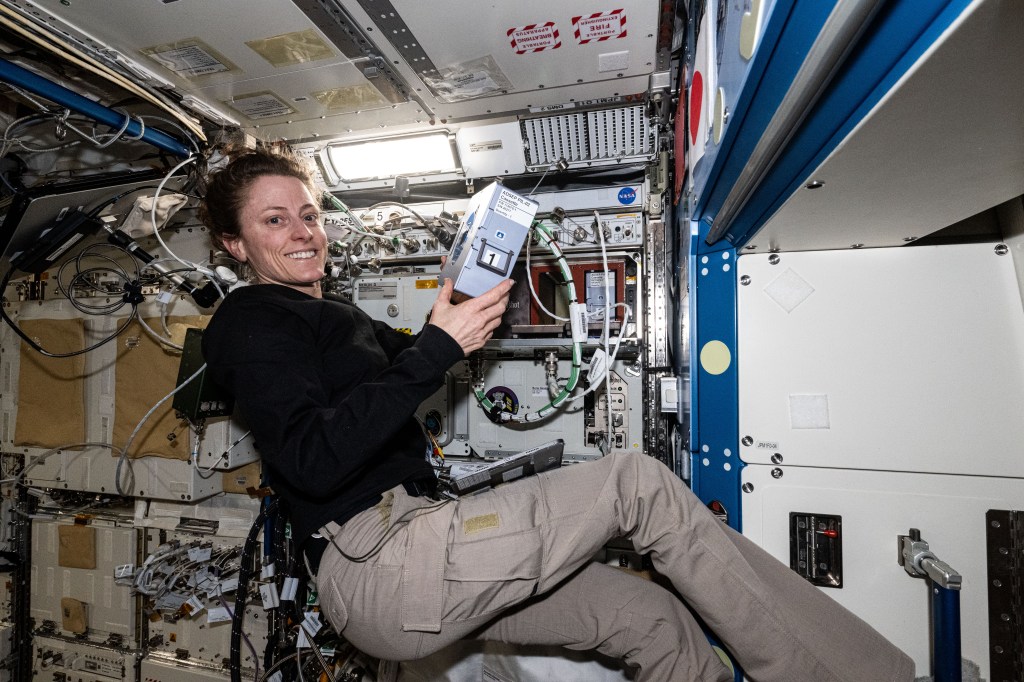 Expedition 70 Flight Engineer and NASA astronaut Loral O'Hara shows off the Advanced Space Experiment Processor-2, or ADSEP-2. The scientific device can interface with the Dragon and Cygnus cargo craft and houses cassettes that process samples for biology and physics research including cell and tissue culturing, protein crystal growth, microorganism and bacteria studies, and materials science research.