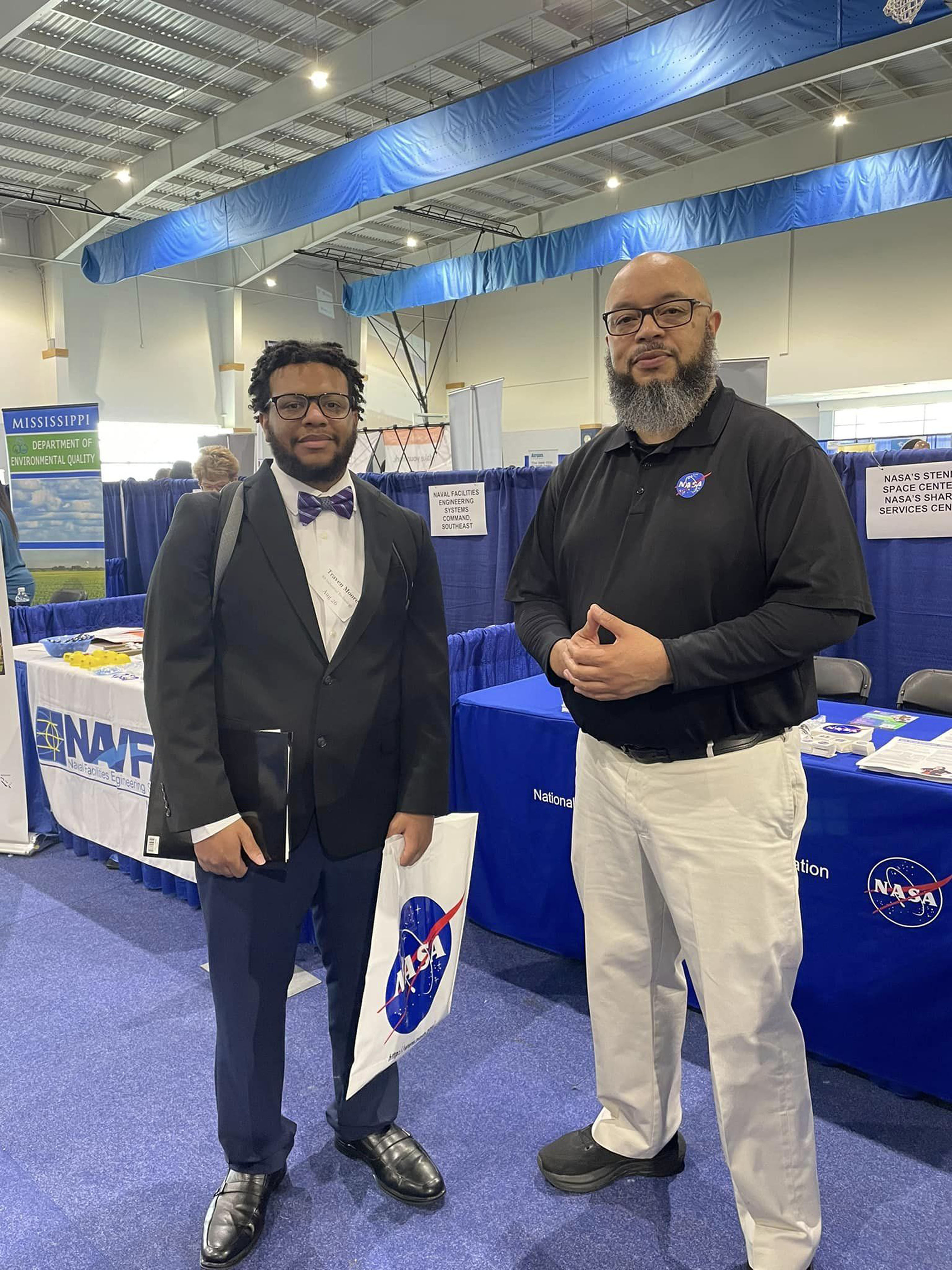 two men pose for photo in front of the NASA table at the career expo event