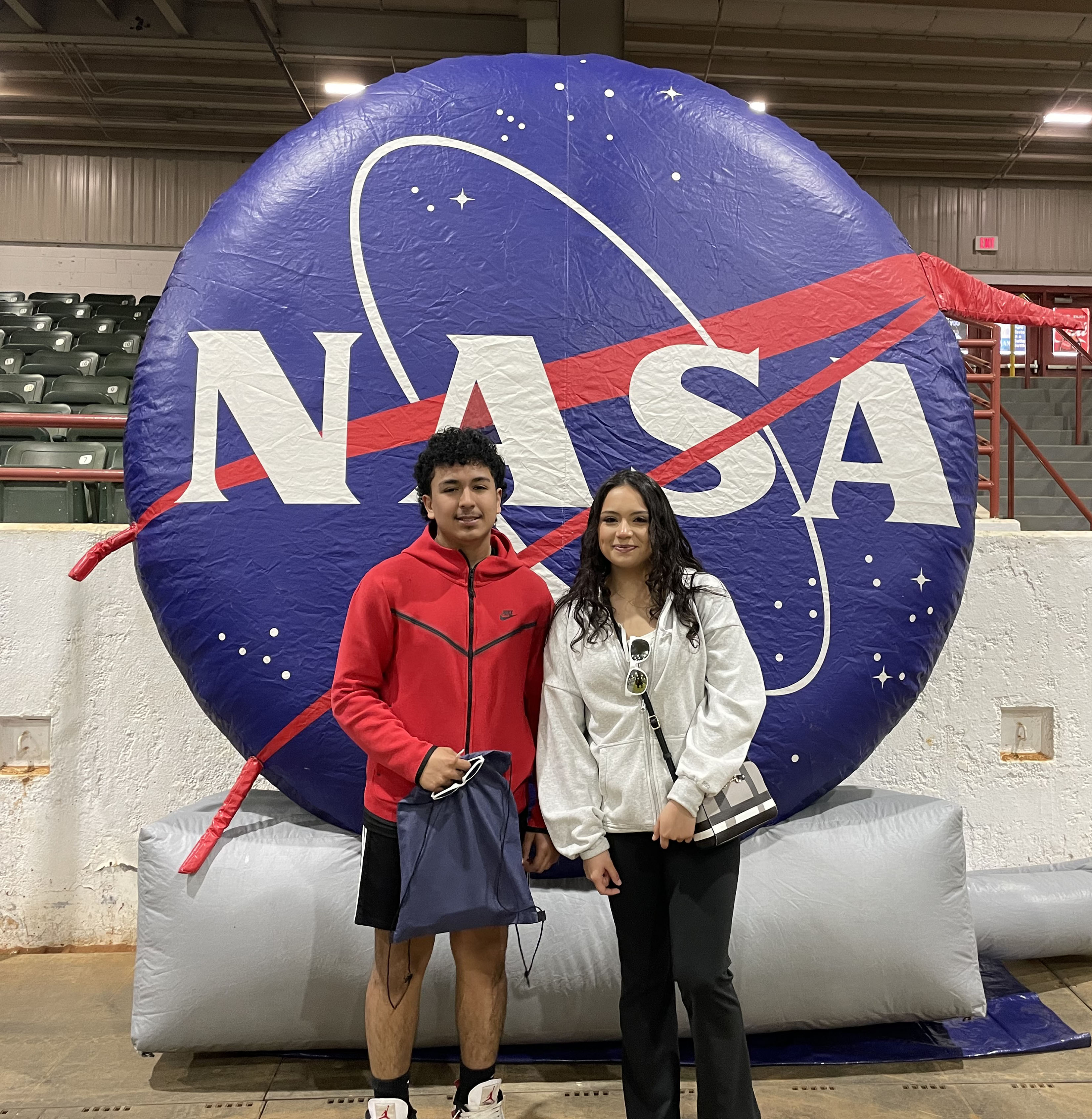 Two event-goers pose for an image in front the NASA meatball inflatable