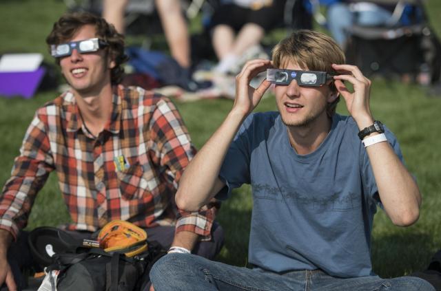 People are seen as they watch a total solar eclipse through protective glasses in Madras, Oregon on Monday, Aug. 21, 2017. A total solar eclipse swept across a narrow portion of the contiguous United States from Lincoln Beach, Oregon to Charleston, South Carolina.