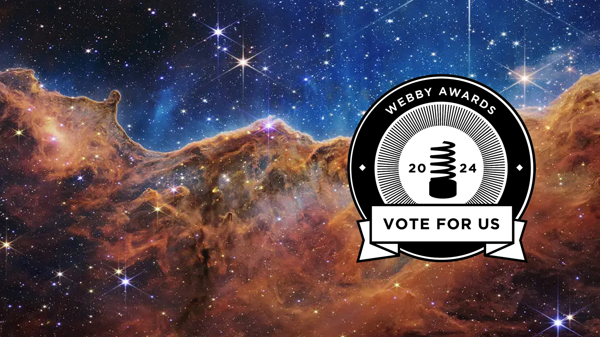 A circular black and white logo with "Webby Awards" around the top, "Vote for Us" near the bottom, and "2024" and a stylized version of the Webby Award in the center is visible as a right-aligned overlay to an image of the Carina Nebula from the James Webb Telescope. That image is divided horizontally by an undulating line between a cloudscape forming a nebula along the bottom portion and a comparatively clear upper portion. Speckled across both portions is a starfield, showing innumerable stars of many sizes. The smallest of these are small, distant, and faint points of light. The largest of these appear larger, closer, brighter, and more fully resolved with 8-point diffraction spikes. The upper portion of the image is blueish, and has wispy translucent cloud-like streaks rising from the nebula below. The orangish cloudy formation in the bottom half varies in density and ranges from translucent to opaque. The stars vary in color, the majority of which have a blue or orange hue. The cloud-like structure of the nebula contains ridges, peaks, and valleys – an appearance very similar to a mountain range. Three long diffraction spikes from the top right edge of the image suggest the presence of a large star just out of view. Credits: NASA, ESA, CSA, and STScI