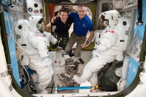iss058e015358 (Feb. 17 2019) --- Astronauts (from left) Anne McClain and David Saint Jacques are pictured in between a pair of spacesuits that are stowed and serviced inside the Quest airlock where U.S. spacewalks are staged.