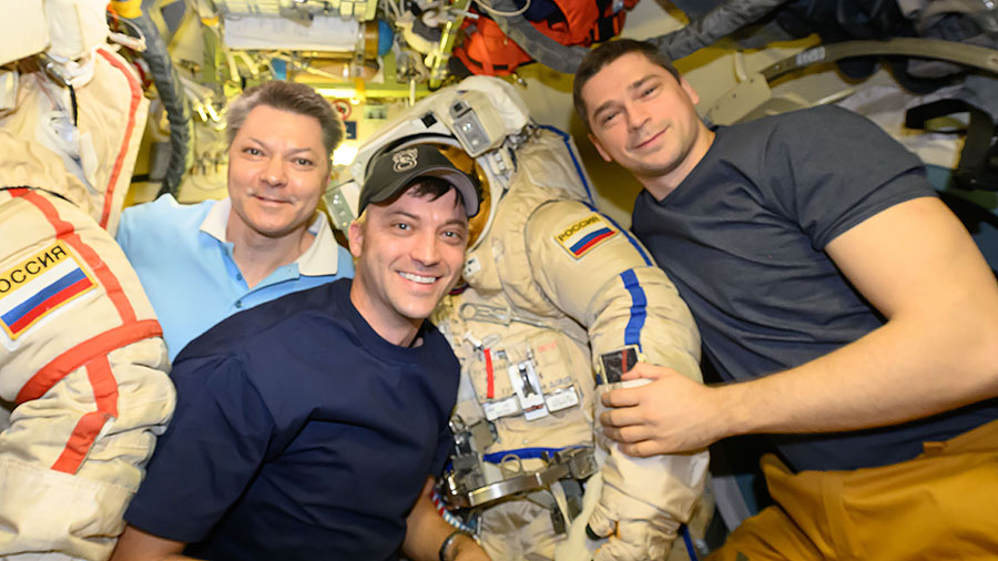 Astronaut Matthew Dominick (center) poses with cosmonauts Oleg Kononenko (left) and Flight Engineer Nikolai Chub (right) while preparing Orlan spacesuits for a spacewalk.