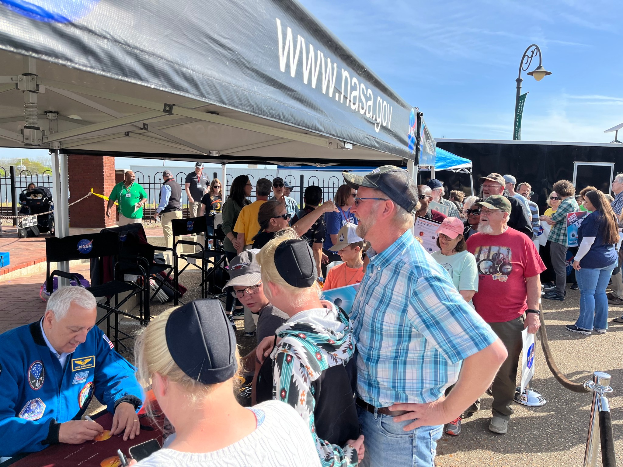 Retired NASA astronaut Mike Massimo, seated left, greets the crowd during the total solar eclipse celebration in Russellville, Arkansas.