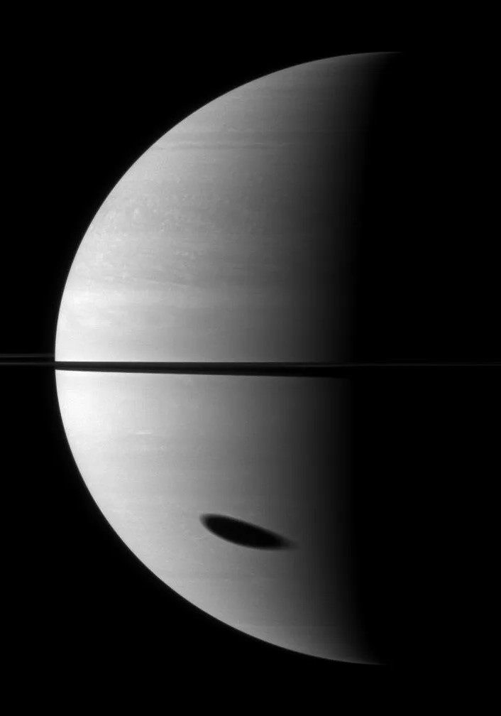 Titan casts its shadow, elongated by the planet's curvature, on Saturn in this November 2009 image from the Cassini orbiter