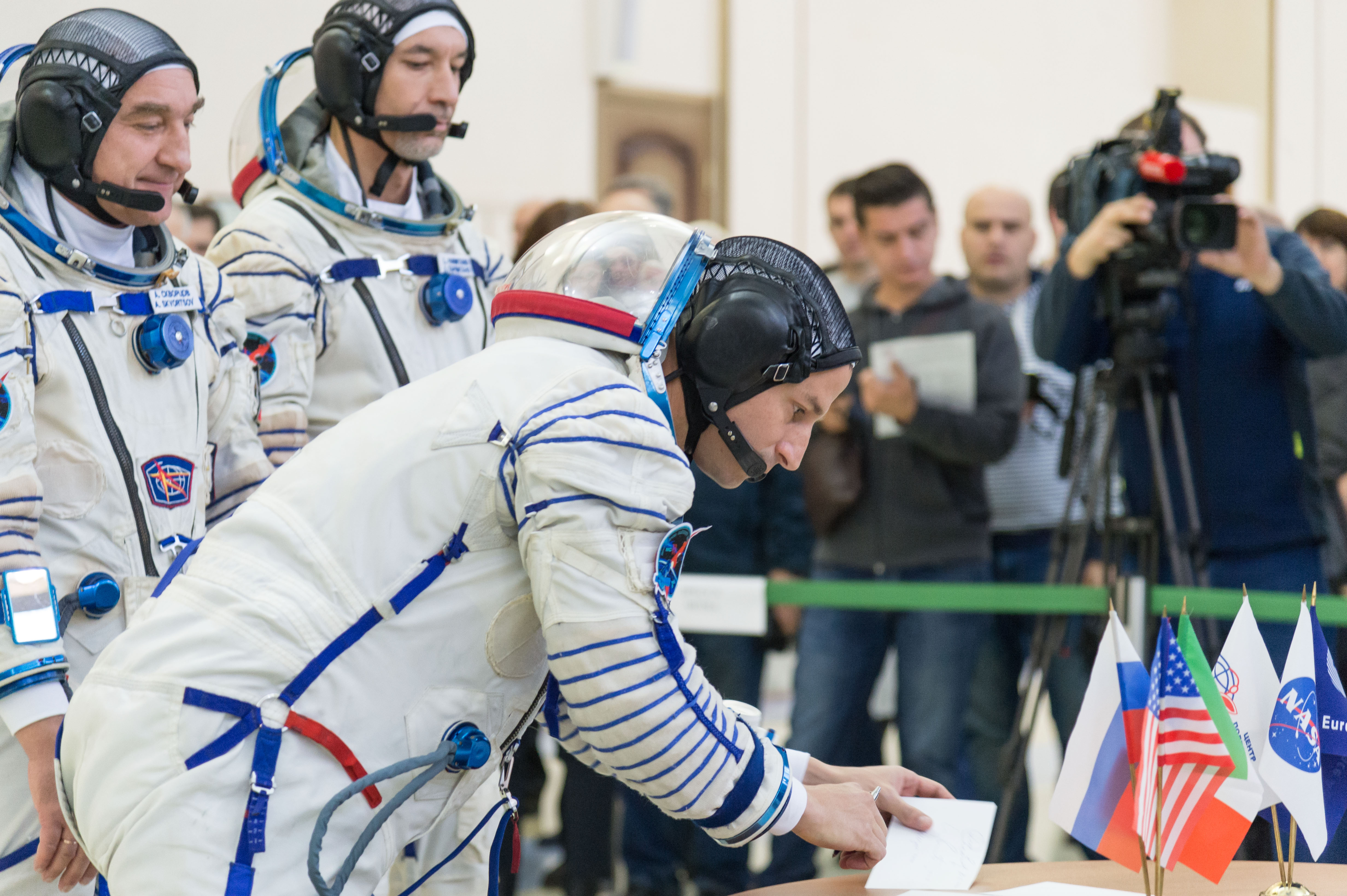 jsc2018e094958 (Nov. 13, 2018) --- At the Gagarin Cosmonaut Training Center in Star City, Russia, Expedition 58 backup crew member Drew Morgan of NASA signs in for qualification exams Nov. 13 as his crewmates, Alexander Skvortsov of Roscosmos (left) and Luca Parmitano of the European Space Agency (right) look on. They are the backups to the prime crew, Oleg Kononenko of Roscosmos, Anne McClain of NASA and David Saint-Jacques of the Canadian Space Agency, who will launch Dec. 3 on the Soyuz MS-11 spacecraft from the Baikonur Cosmodrome in Kazakhstan for a six-and-a-half month mission on the International Space Station. Credit: NASA/Sarah Volkman