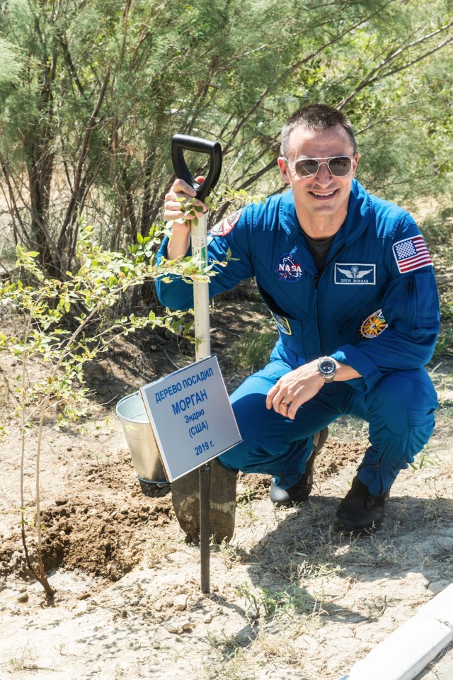 jsc2019e039261 (July 12, 2019) --- At the Cosmonaut Hotel crew quarters in Baikonur, Kazakhstan, Expedition 60 crewmember Drew Morgan of NASA poses for pictures July 12 after planting a tree in his name as part of pre-launch activities. Morgan, Alexander Skvortsov of Roscosmos and Luca Parmitano of the European Space Agency will launch July 20 on the Soyuz MS-13 spacecraft from the Baikonur Cosmodrome in Kazakhstan on a mission to the International Space Station. Credit: Andrey Shelepin/GCTC