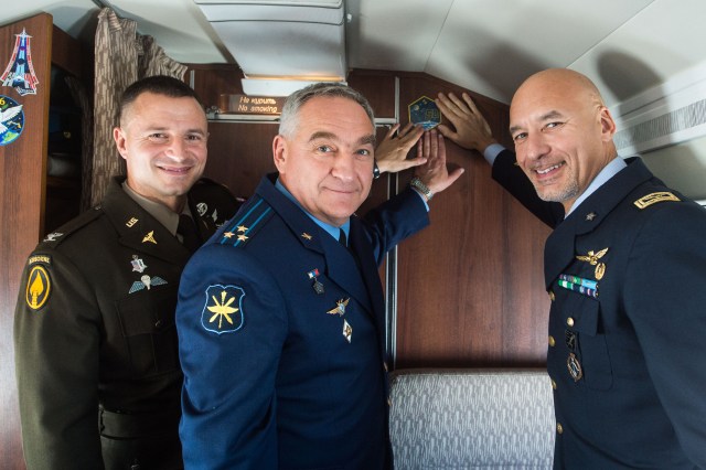 jsc2019e038367 (July 4, 2019) --- Aboard a Gagarin Cosmonaut Training Center aircraft, Expedition 60 crewmembers Drew Morgan of NASA (left), Alexander Skvortsov of Roscosmos (center) and Luca Parmitano of the European Space Agency (right) affix a crew insignia sticker to the hull of the plane as they flew to their training base in Kazakhstan July 4. They will launch July 20 from the Baikonur Cosmodrome in Kazakhstan on the Soyuz MS-13 spacecraft for a mission on the International Space Station. Credit: Andrey Shelepin/GCTC