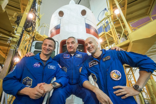 jsc2019e039427 (July 16, 2019) --- At the Baikonur Cosmodrome in Kazakhstan, Expedition 60 crewmembers Drew Morgan of NASA (left), Alexander Skvortsov of Roscosmos (center) and Luca Parmitano of the European Space Agency (right) pose for pictures in front of the Soyuz MS-13 spacecraft July 16 as part of pre-launch preparations. They will launch July 20 on the Soyuz MS-13 spacecraft from the Baikonur Cosmodrome for a mission on the International Space Station. Credit: Andrey Shelepin/GCTC